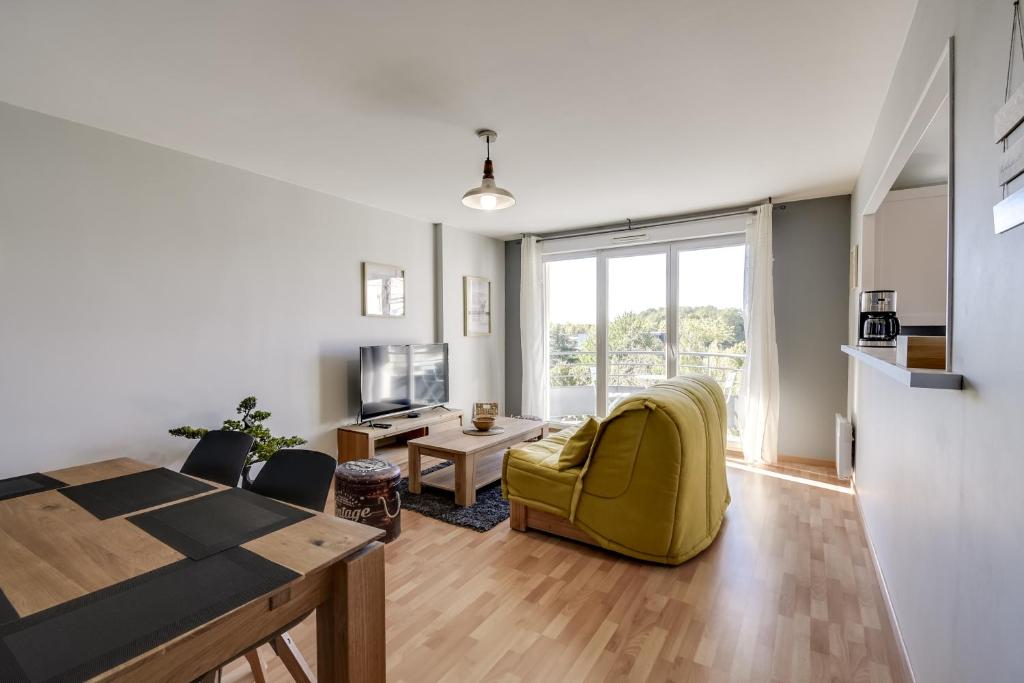 a living room with a yellow chair and a table at Chic apart avec terrace et parking in Cergy