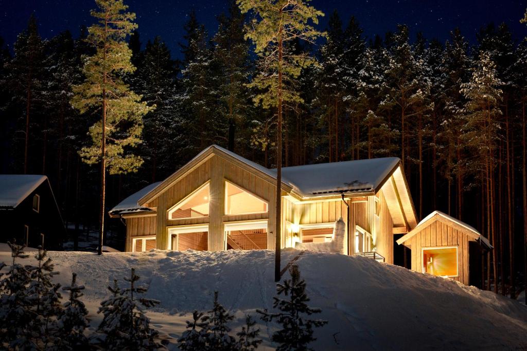 uma casa de madeira na neve à noite em Moderne hytte met eindeloos uitzicht en een sauna em Vradal