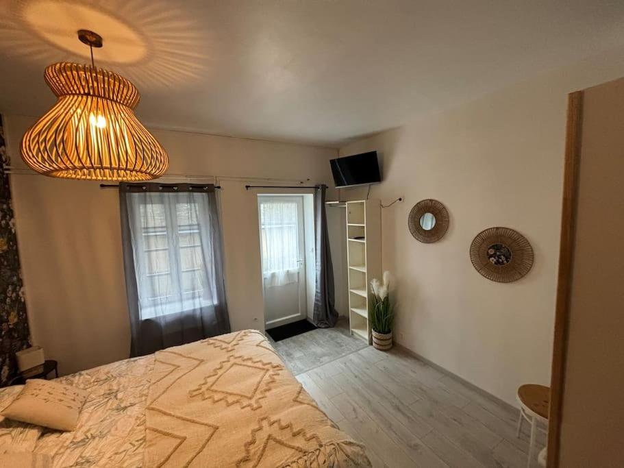 1 dormitorio con cama y lámpara de araña en Le studio «des Terroux », 