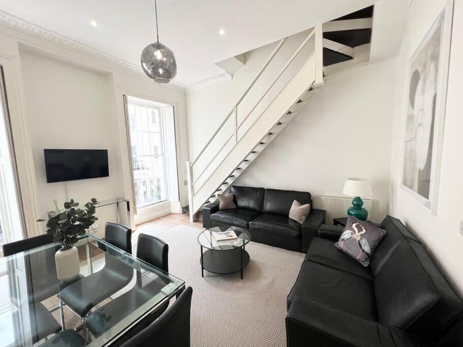 sala de estar con sofá negro y escalera en Split Level 3 Bed- Hyde Park, en Londres