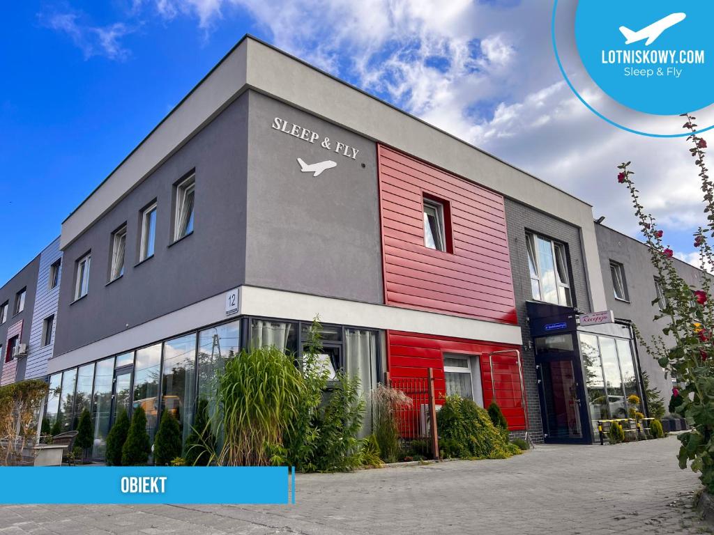 a store front with a red and gray building at Sleep&Fly in Gdańsk-Rębiechowo