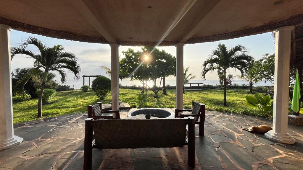 a porch with a table and chairs and palm trees at Room in Villa - Eagle Suite 38m2 in Villa 560 m2, Indian Ocean View in Shimoni