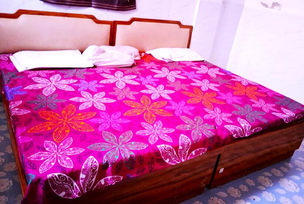 a bed with a pink bedspread with flowers on it at GRG Kameshwar Bhawan Rajgir in Rājgīr