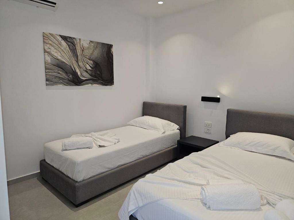 two beds in a room with a painting on the wall at Adele Hotel Ksamil in Ksamil