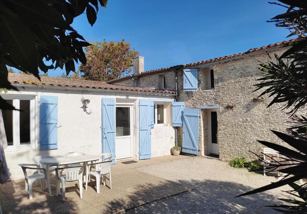 a patio with a table and chairs in front of a building at La petite Grange - Parking privé - A 2km de la mer in Saint-Georges-dʼOléron