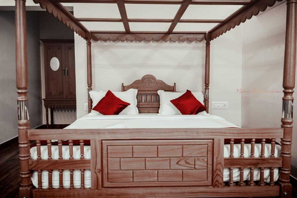 een slaapkamer met een hemelbed met rode kussens bij ATHIRAPPILY SREENILAYAM HERITAGE RESORt in Athirappilly