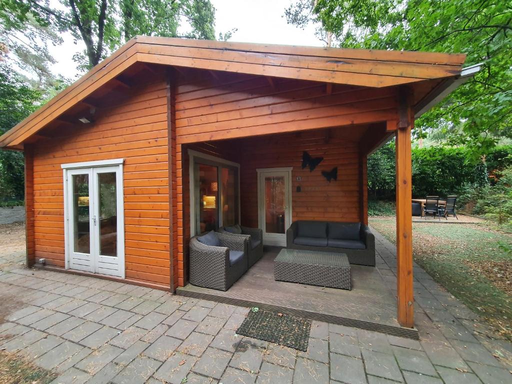 een grote houten schuur met banken en een patio bij Chalet Ermelo in Ermelo