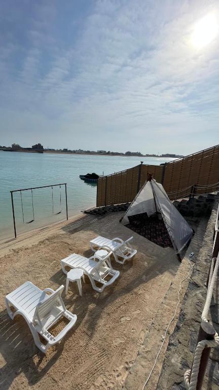 eine Gruppe Stühle und ein Zelt am Strand in der Unterkunft درة العروس فيلا فاخره بمسبح داخلي in Durrat Al-Arus