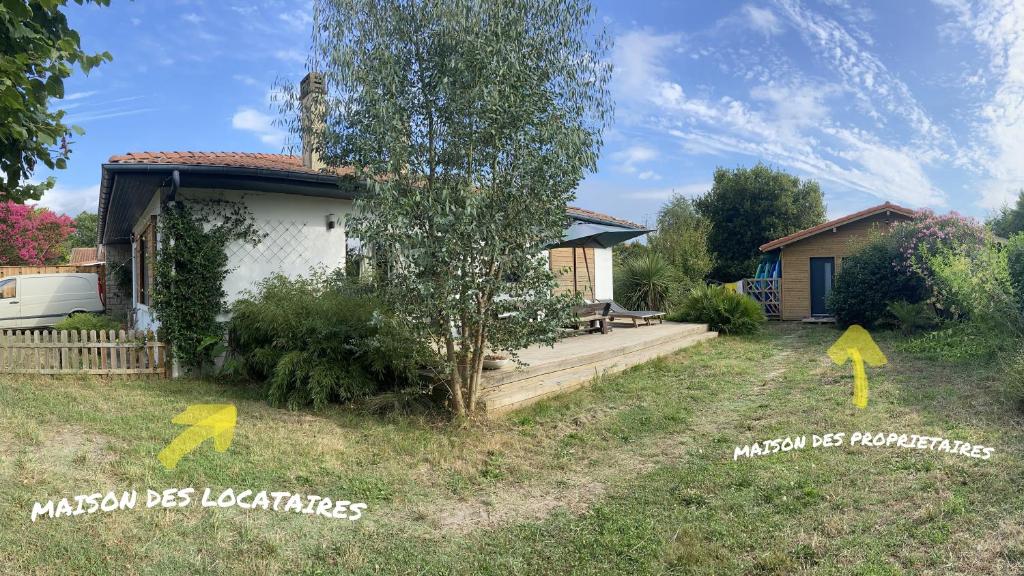 a house with a tree and two yellow arrows at Seignosse : Mandago Surf Home in Seignosse