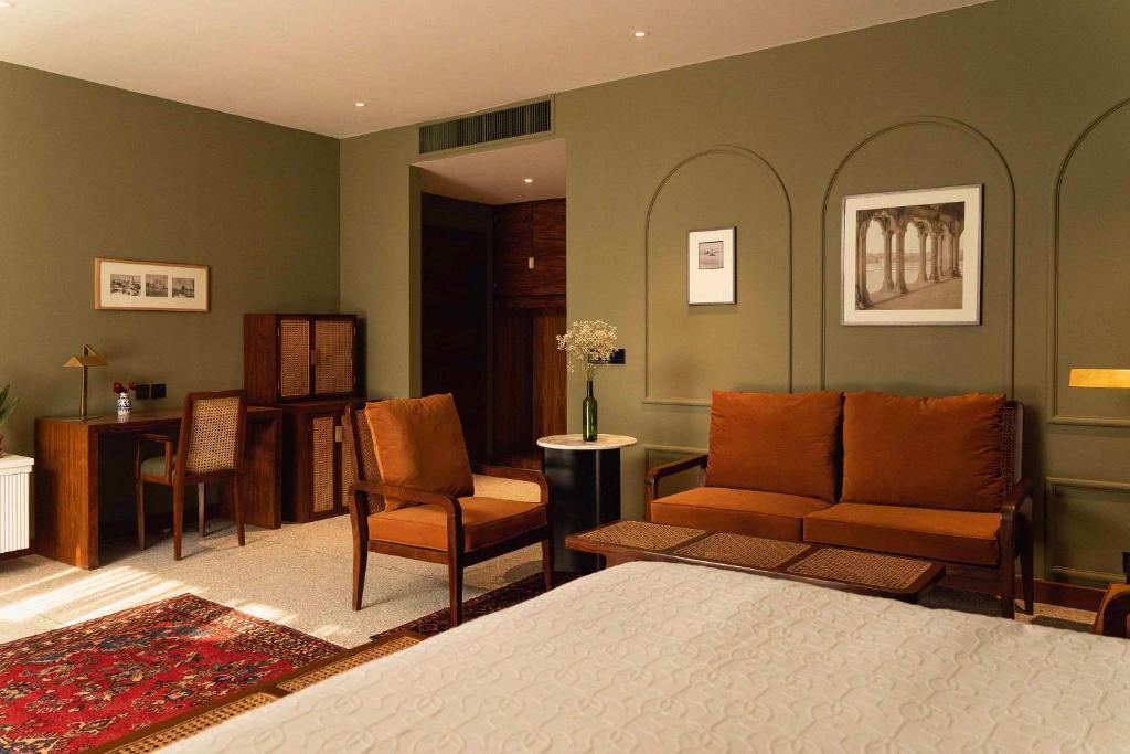 a bedroom with a bed and chairs and a desk at The Fred Hotel in Lahore