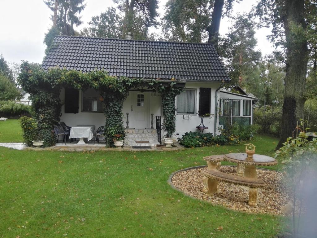 a small white house with a fountain in the yard at Ferienhaus Schatz in Siedlung Schönwalde
