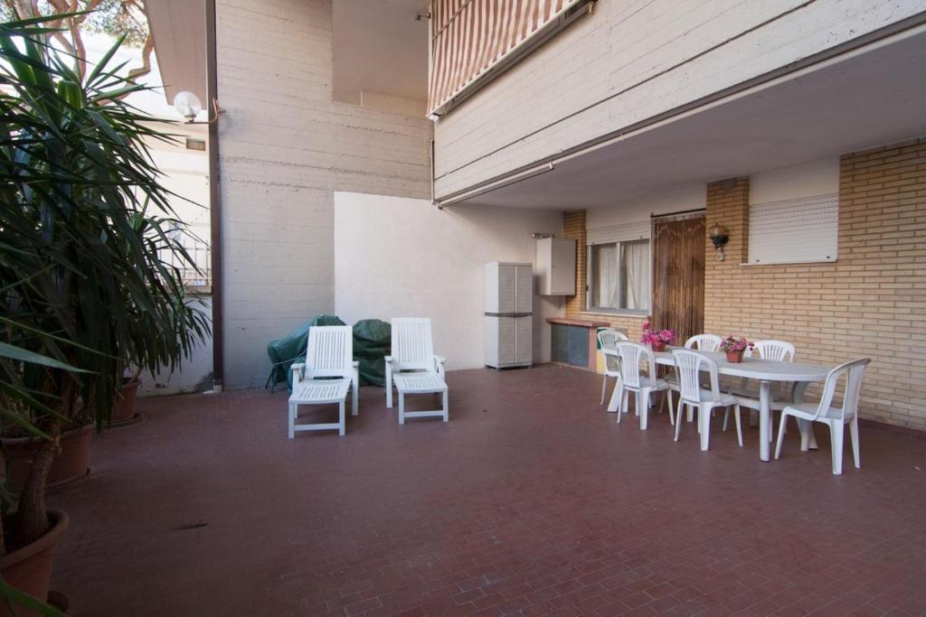 Il dispose d'une cuisine et d'une terrasse avec des chaises blanches et une table. dans l'établissement Appartamento BC, à Follonica