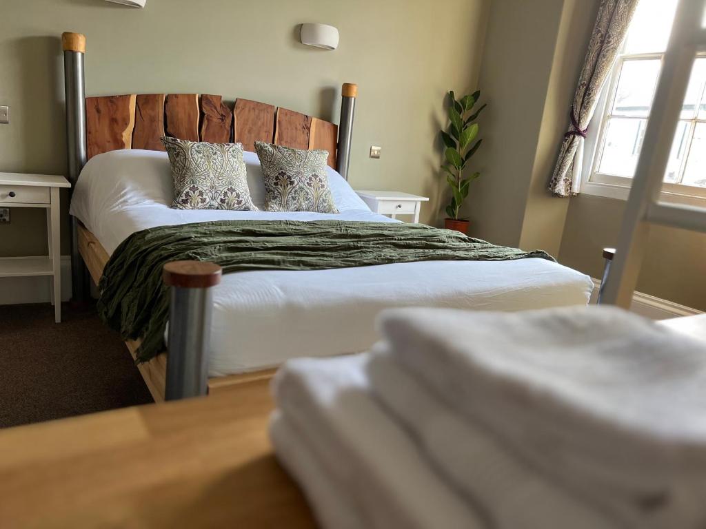 Schlafzimmer mit einem Bett mit weißer Bettwäsche und Kissen in der Unterkunft The Roost in Cullompton