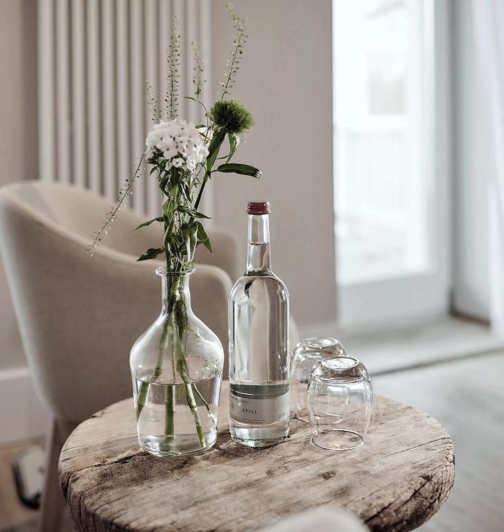 a bottle of wine and a vase of flowers on a table at The Cozy Hotel & Lofts Timmendorfer Strand in Timmendorfer Strand