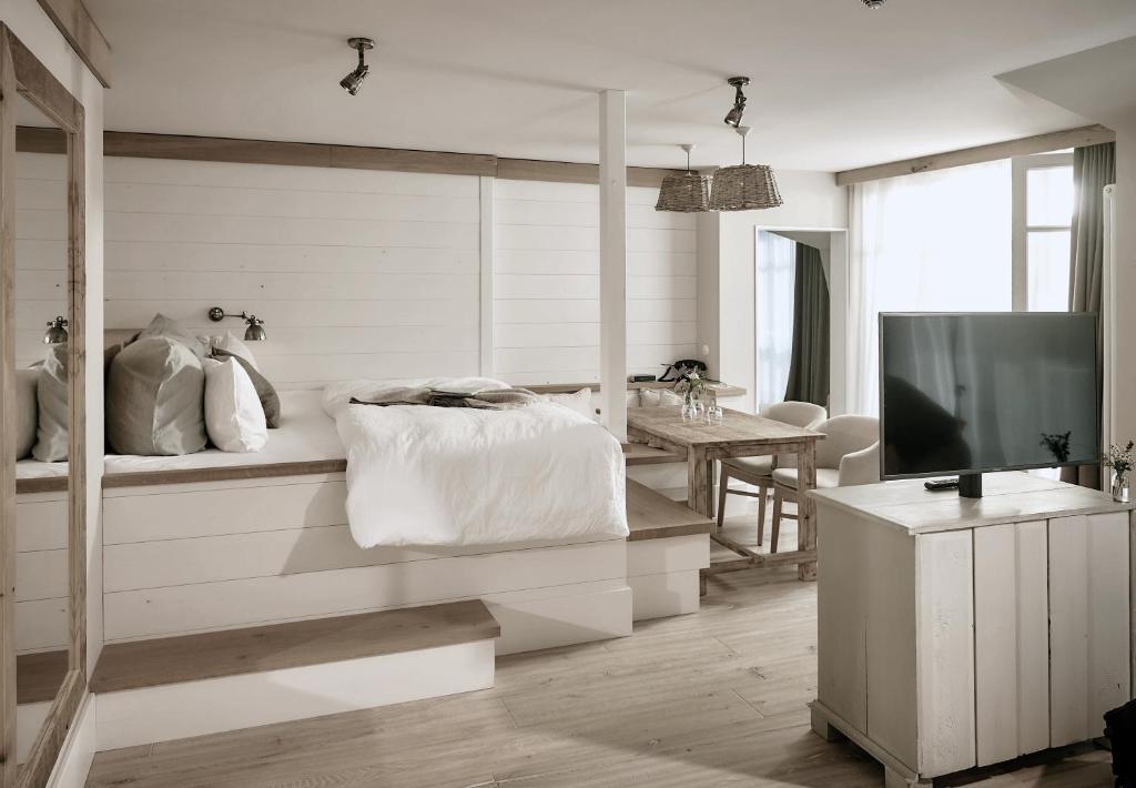 a white bedroom with a bed and a television at The Cozy Hotel & Lofts Timmendorfer Strand in Timmendorfer Strand