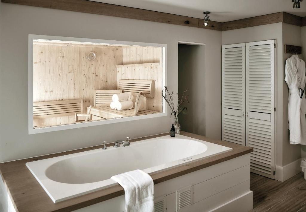 a white bath tub in a bathroom with a mirror at The Cozy Hotel & Lofts Timmendorfer Strand in Timmendorfer Strand