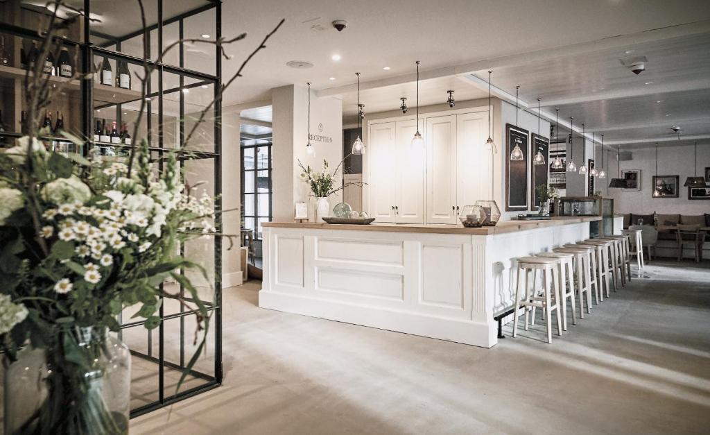 a kitchen with white cabinets and a counter with chairs at The Cozy Hotel & Lofts Timmendorfer Strand in Timmendorfer Strand