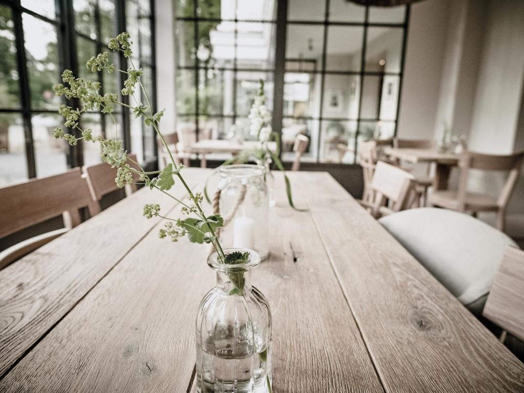 a vase with flowers sitting on a wooden table at The Cozy Hotel & Lofts Timmendorfer Strand in Timmendorfer Strand