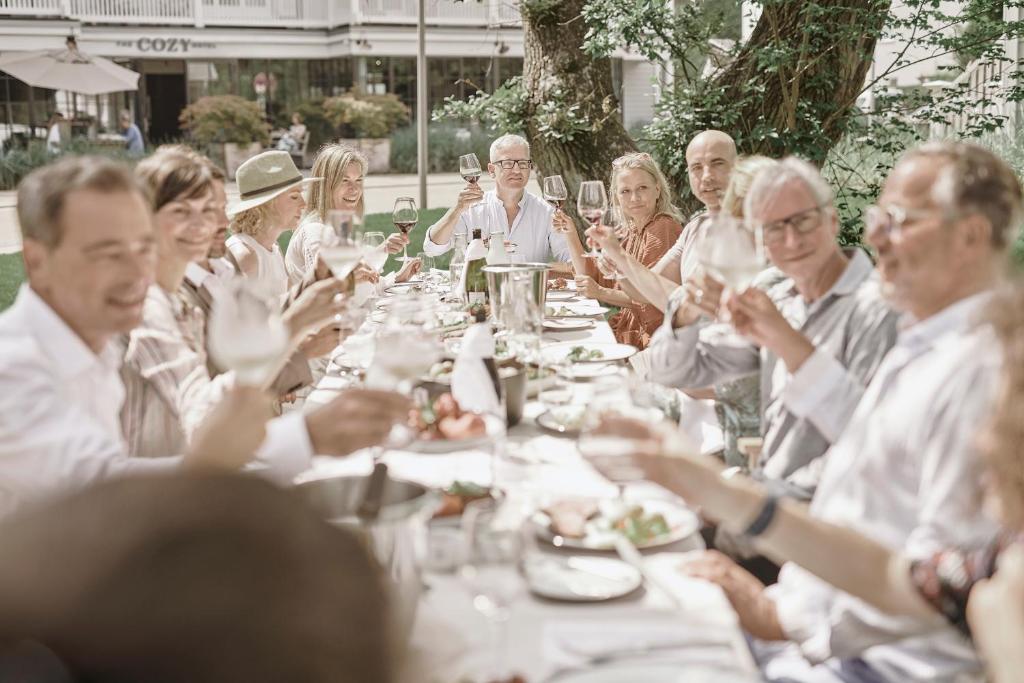 a group of people sitting around a long table at The Cozy Hotel & Lofts Timmendorfer Strand in Timmendorfer Strand