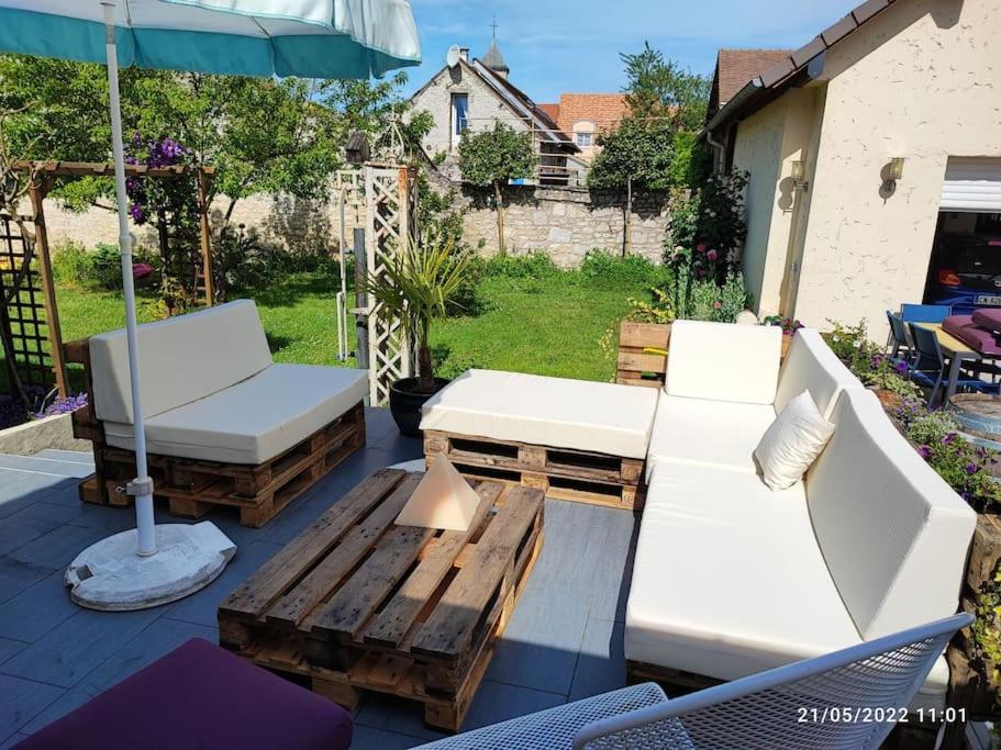 a patio with two couches and a table and an umbrella at Grande maison de campagne in Villiers-en-Désoeuvre