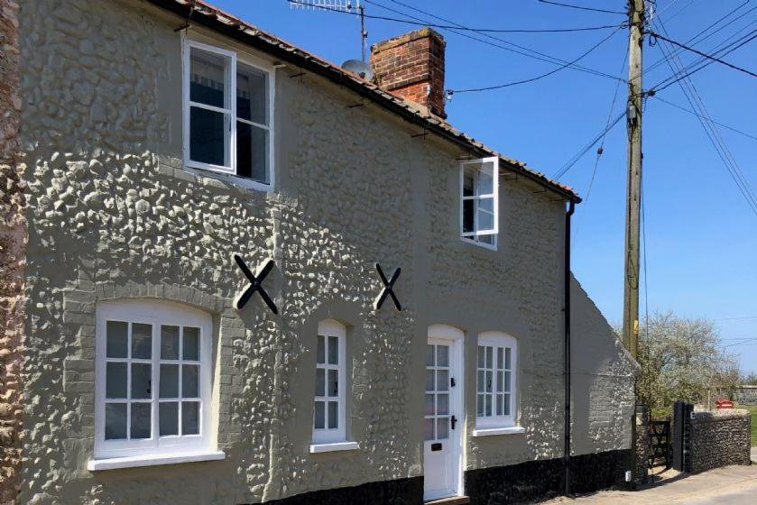 a building with a cross painted on the side of it at Three Tuns Cottage in Little Walsingham