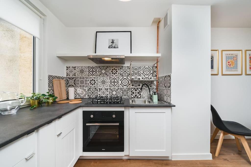 a kitchen with white cabinets and black appliances at Close to everywhere, cosy place in Krakow