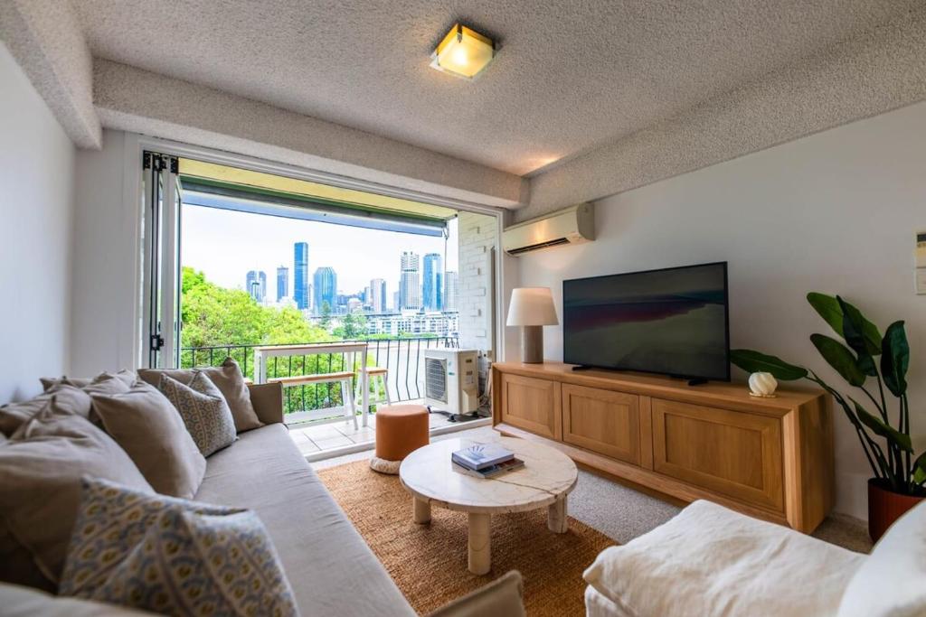 a living room with a couch and a flat screen tv at Riverside apartment with city & Story Bridge view in Brisbane