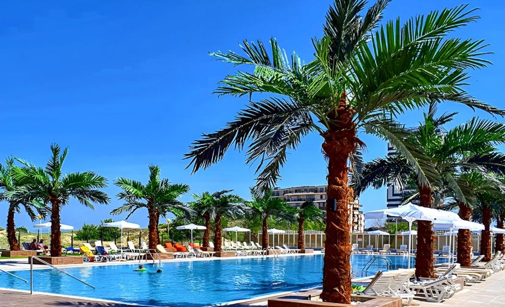 a swimming pool with palm trees and lounge chairs at Europe Hotel & Casino All Inclusive in Sunny Beach