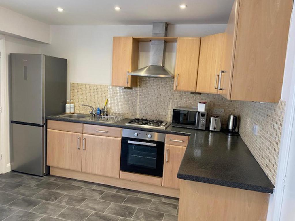 a kitchen with wooden cabinets and a stainless steel refrigerator at Manchester Home near Near City center and Stadium in Manchester