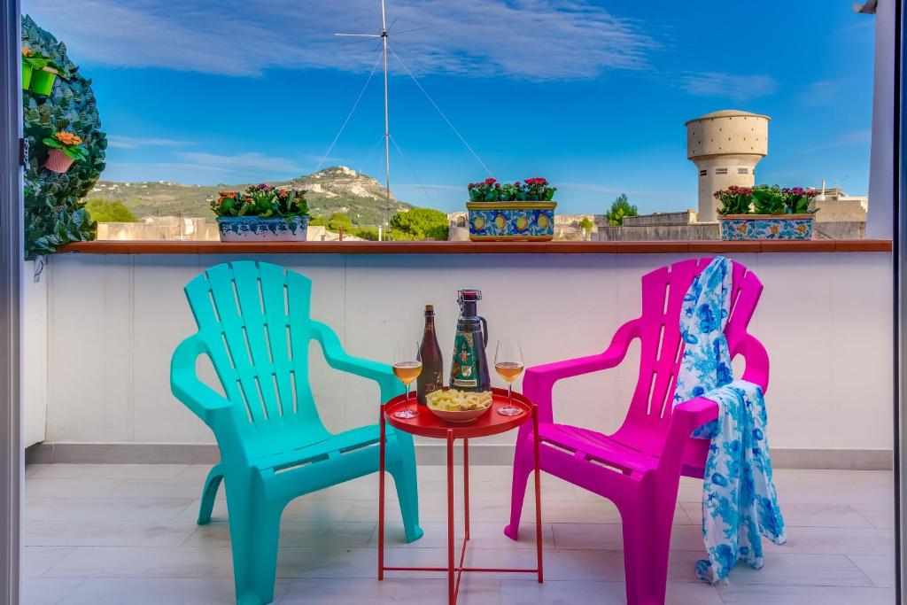 zwei Stühle und ein Tisch mit einem Glas Wein in der Unterkunft Scenario Holiday's Home in Sciacca