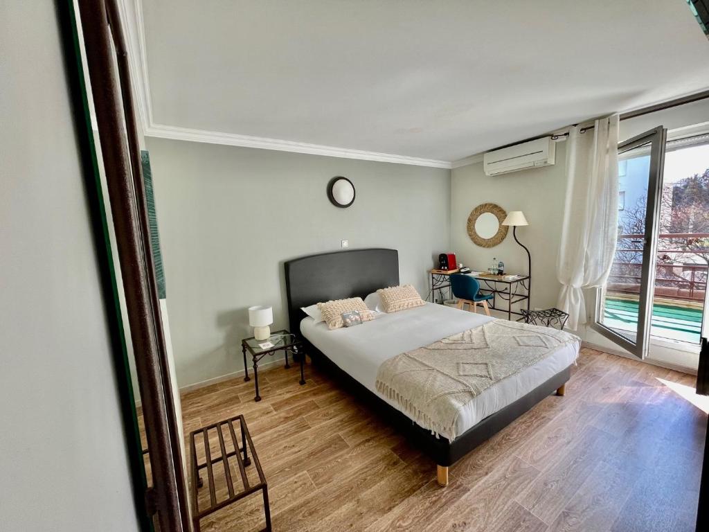 a bedroom with a bed and a large window at Hôtel Ulysse Montpellier Centre in Montpellier