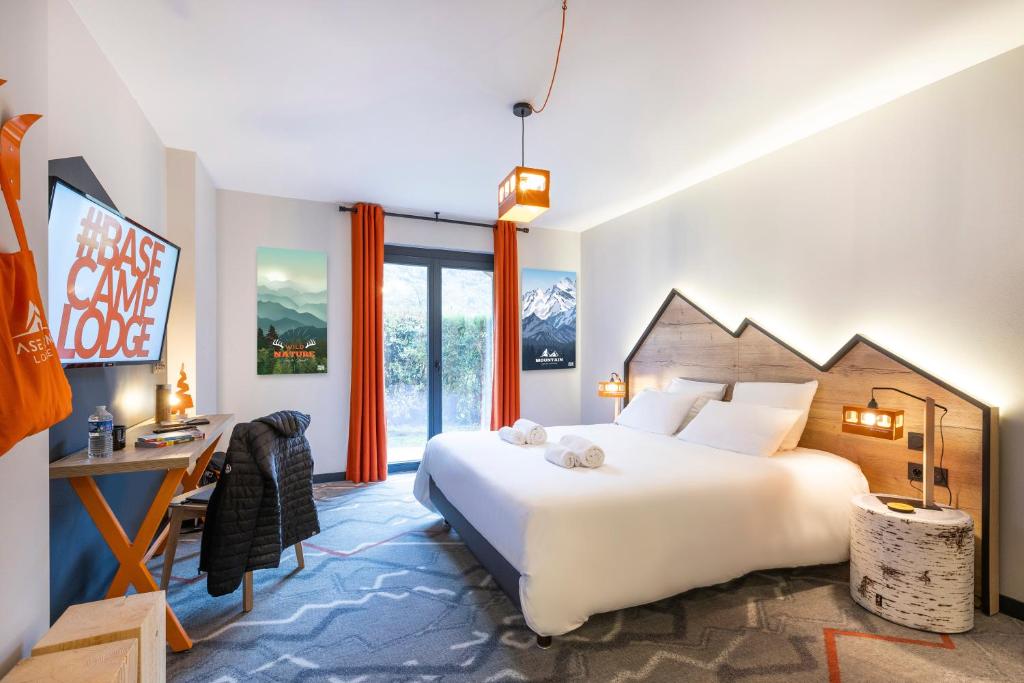 a bedroom with a large white bed and a desk and window at Hotel Base Camp Lodge - Albertville in Albertville