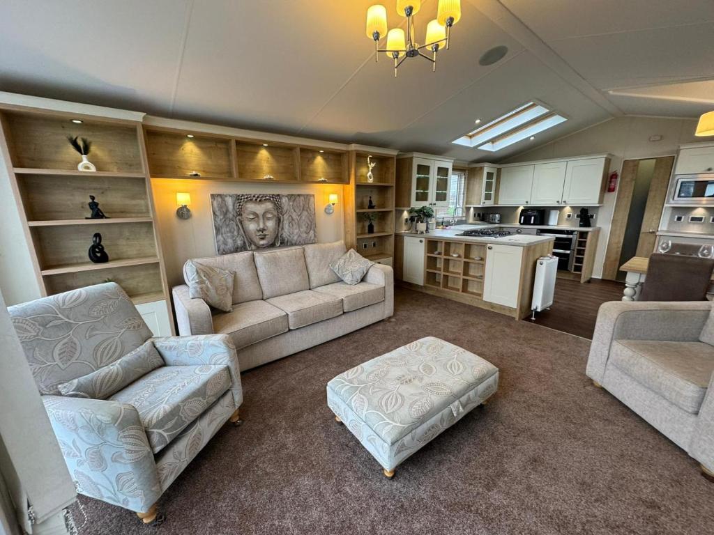 a living room with two couches and a kitchen at Golden Anchor - The Vogue - Coastal Caravan Breaks in Chapel Saint Leonards