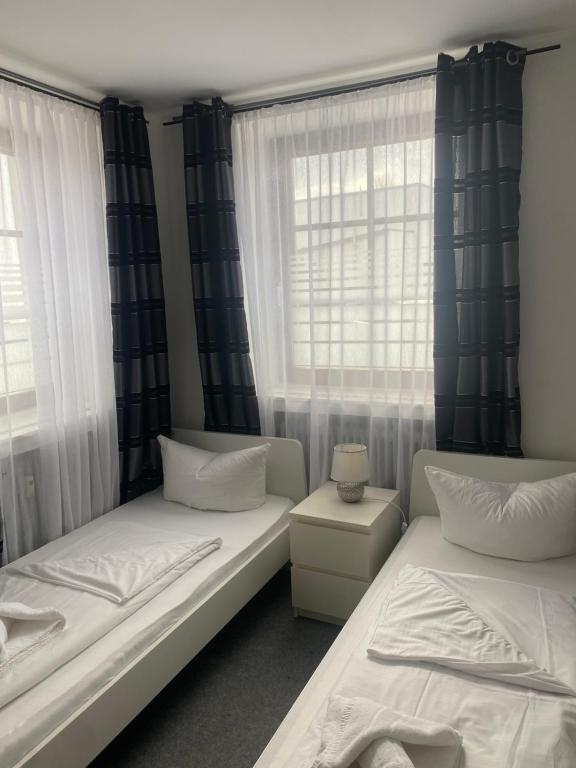 two beds in a room with two windows at GoldStar Apartments nähe Messe in Sarstedt