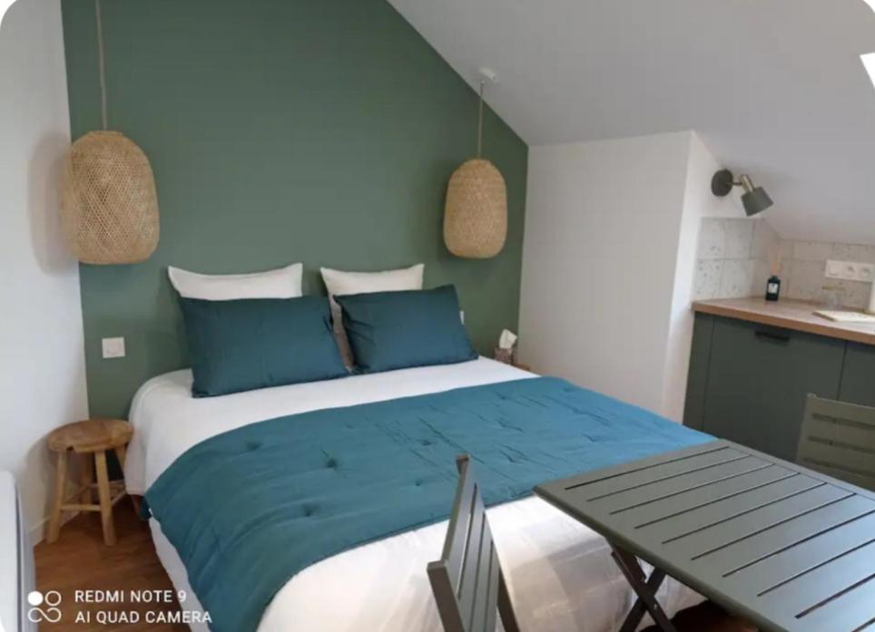 Un dormitorio con una cama con almohadas azules y una mesa. en La Cosy, en Lancé