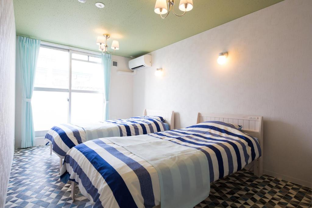 Daikōchōにあるあやきちゲストハウスの青と白のストライプを用いた客室内のベッド3台