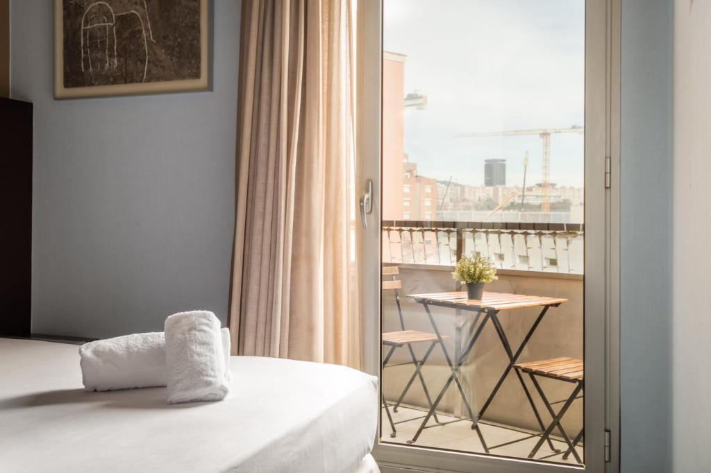 a bedroom with a bed and a balcony with a table at Hotel Madanis in Barcelona