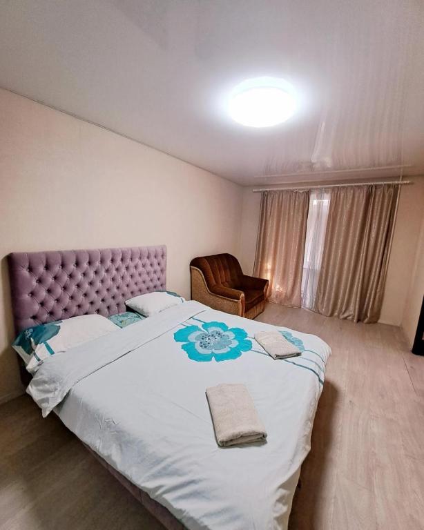 1 dormitorio con 1 cama grande y 1 silla en Студия 2 комнаты в центре города, en Krivoy Rog