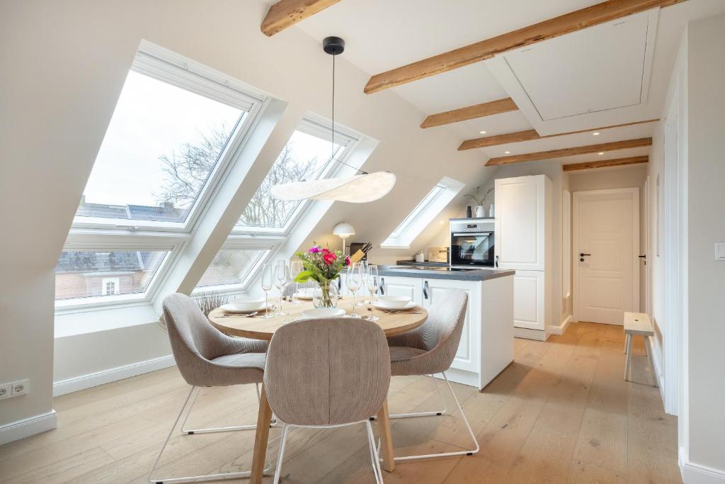 uma cozinha com mesa, cadeiras e janelas em Strandbude Sylt em Westerland
