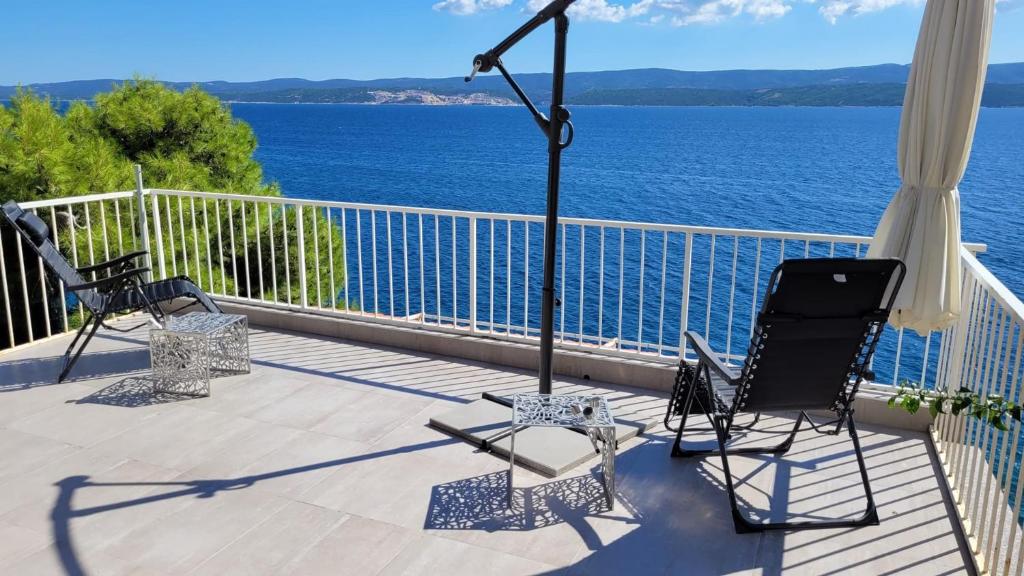 two chairs sitting on a balcony overlooking the water at Apartments Timee first row to beach in Stanići