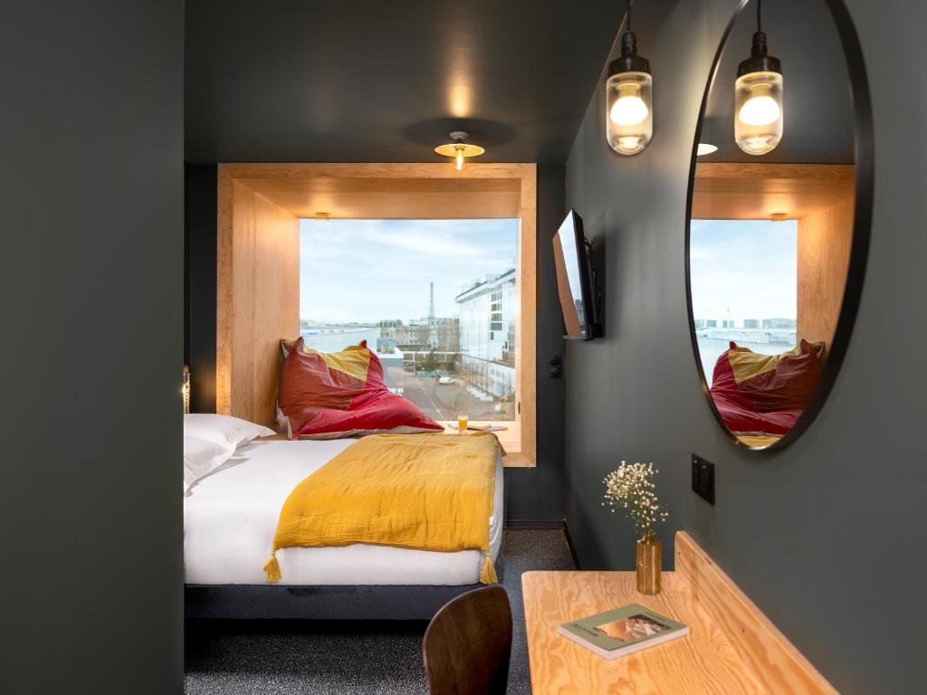a bedroom with a bed and a mirror and a table at Eklo Paris Expo Porte de Versailles in Vanves