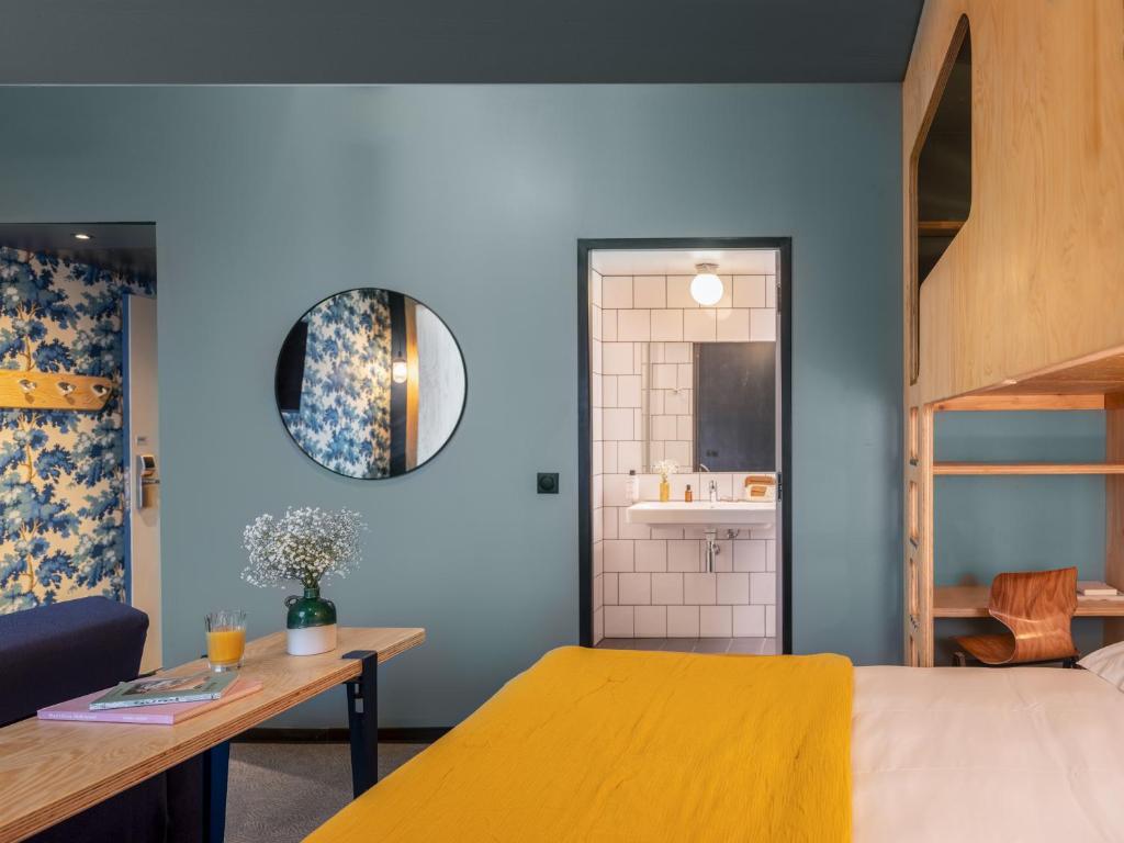 a bedroom with a yellow bed and a bathroom at Eklo Paris Expo Porte de Versailles in Vanves