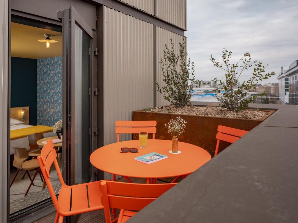 a orange table and chairs on a balcony with a view at Eklo Paris Expo Porte de Versailles in Vanves