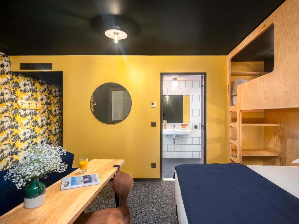 a bedroom with yellow walls and a bed and a table at Eklo Paris Expo Porte de Versailles in Vanves