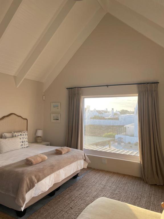 a bedroom with a bed and a large window at Bougain Villa Studio 2 in Paternoster