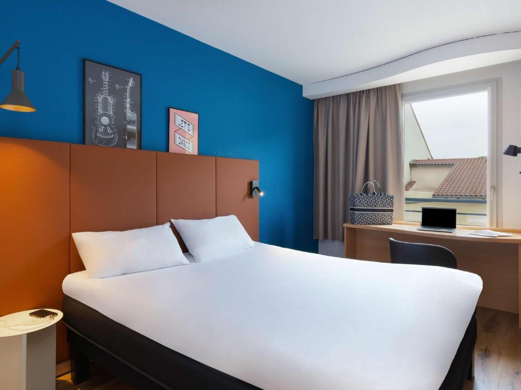 a bedroom with a white bed and a blue wall at ibis Lyon Sud Vienne Saint-Louis in Vienne