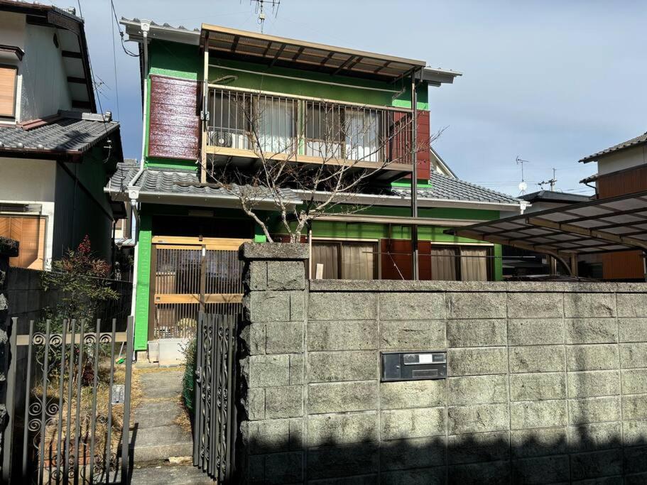 ein Haus mit einem Zaun vor einer Wand in der Unterkunft 高知県　みどりの家 in Gomen