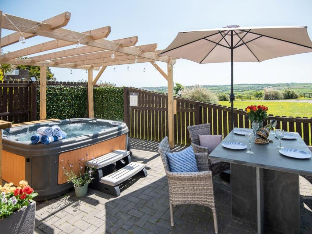 a patio with a hot tub and an umbrella at 2 Bed in Westward Ho 89868 in Westward Ho