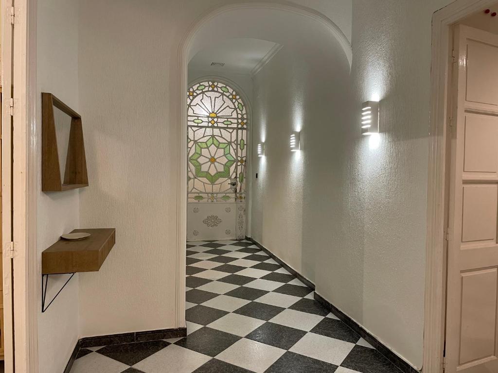 un couloir avec une fenêtre et un sol en damier dans l'établissement Patios de la Carmela, à Isla Cristina