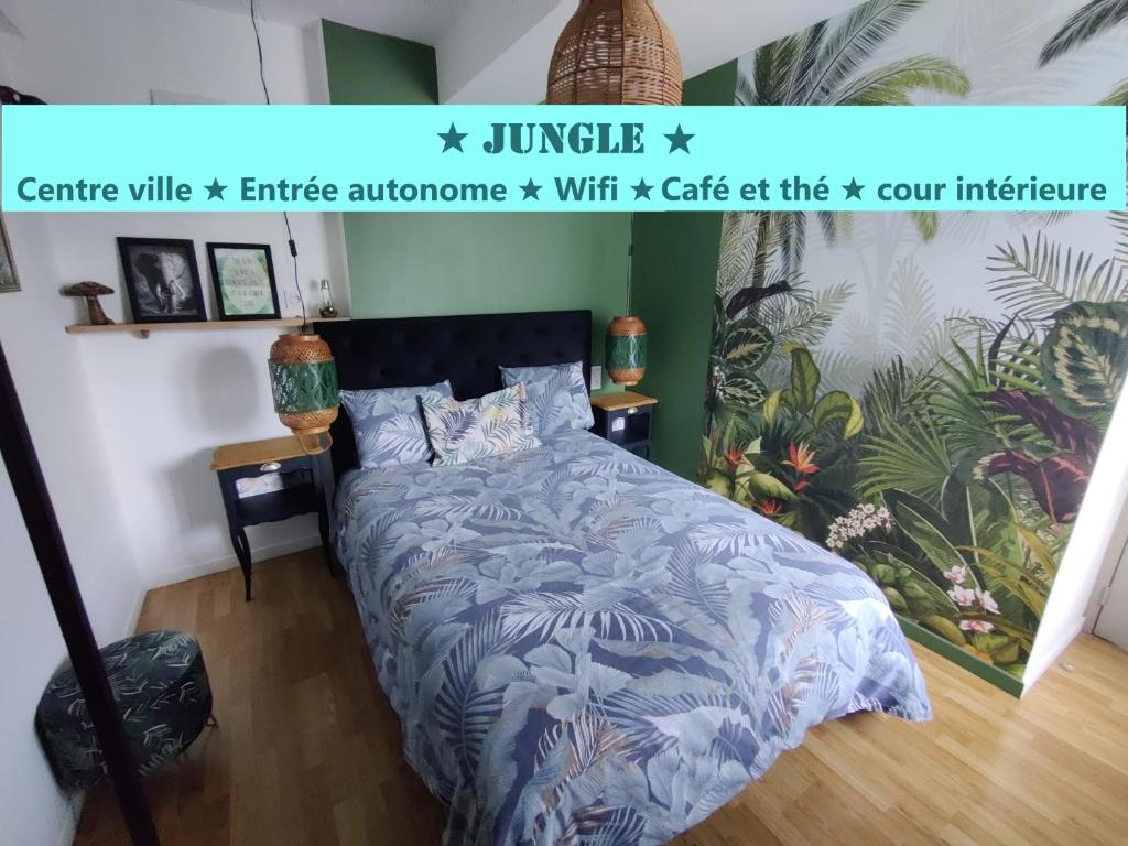 a bedroom with a bed with a blue comforter at Appartement T2 "JUNGLE" Centre Ville de VITRÉ au calme coté cour in Vitré